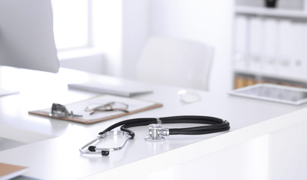 Stetoskooppi ja reseptilomake pöydällä tietokoneen kanssa